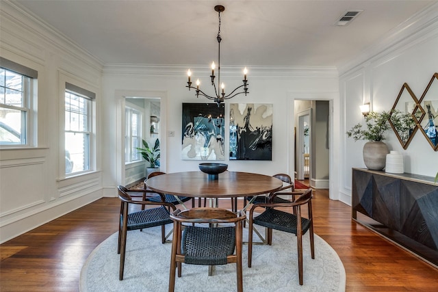 dining area featuring crown molding, dark wood-type flooring, and an inviting chandelier