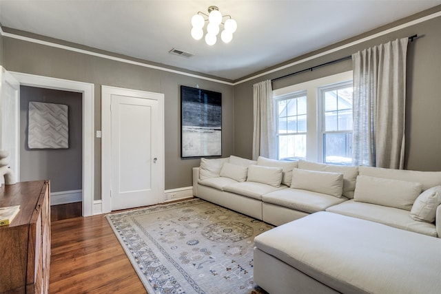 living room featuring hardwood / wood-style flooring, an inviting chandelier, and ornamental molding