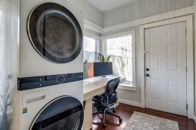 laundry room with a healthy amount of sunlight, dark hardwood / wood-style flooring, and stacked washer and clothes dryer