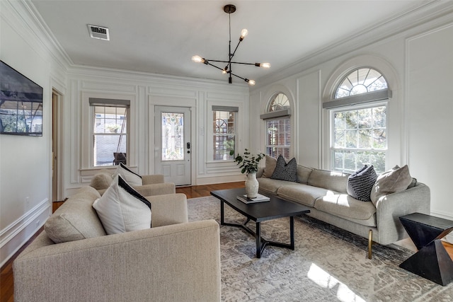 living room featuring light hardwood / wood-style flooring, an inviting chandelier, and ornamental molding