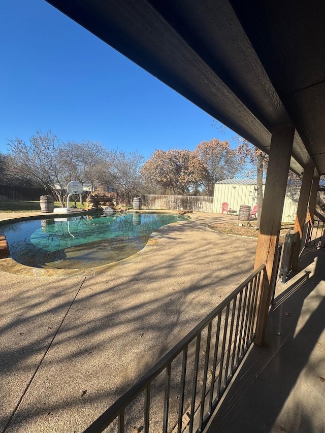 view of swimming pool featuring a shed and a patio area