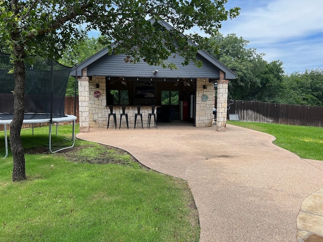 view of home's community featuring a trampoline, a patio area, a lawn, and exterior bar