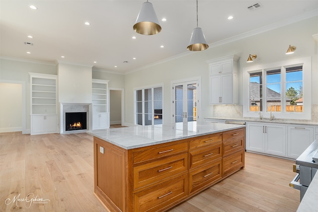 kitchen featuring white cabinetry, decorative light fixtures, light stone counters, and light wood-type flooring