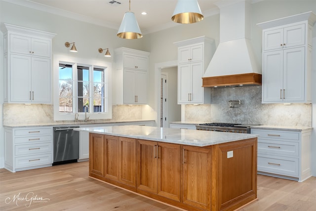 kitchen featuring custom exhaust hood, stainless steel dishwasher, a kitchen island, light wood-style flooring, and crown molding