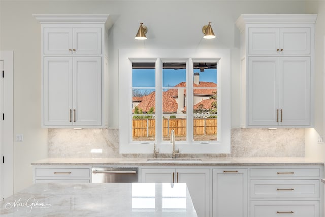 kitchen with sink, white cabinetry, tasteful backsplash, dishwasher, and light stone countertops