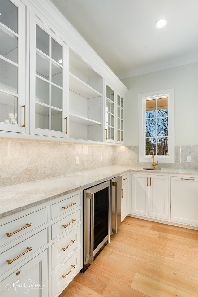 kitchen featuring sink, white cabinets, beverage cooler, decorative backsplash, and light stone countertops