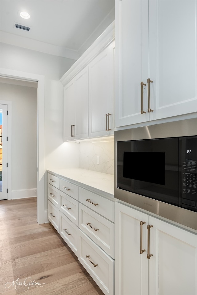 details featuring backsplash, ornamental molding, light hardwood / wood-style floors, and white cabinets