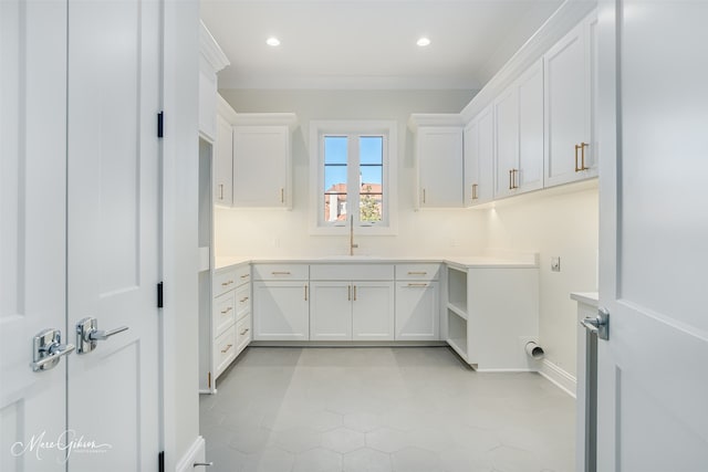 washroom with sink, ornamental molding, and cabinets