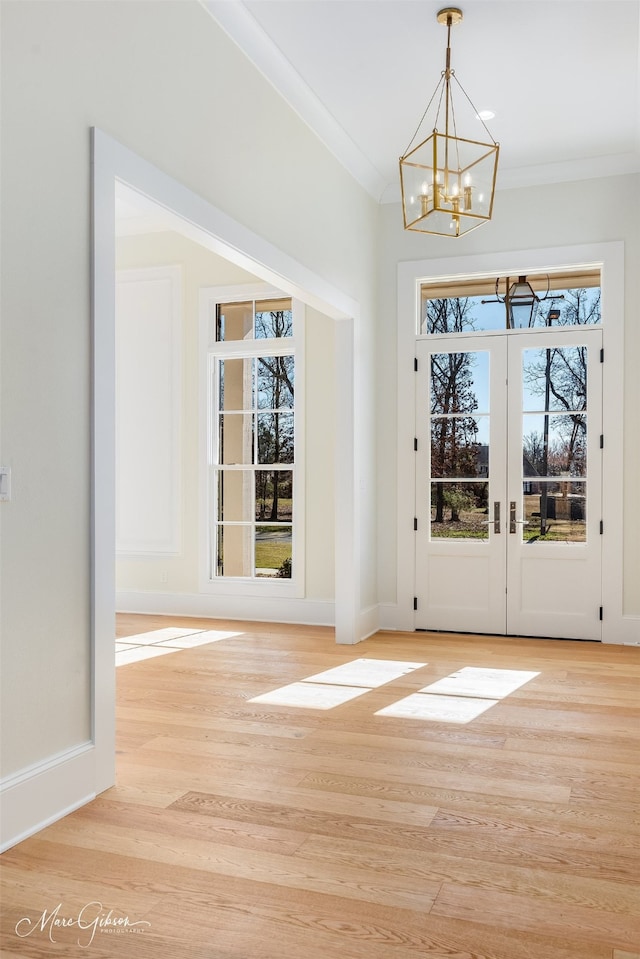 interior space featuring an inviting chandelier, ornamental molding, and light wood-type flooring