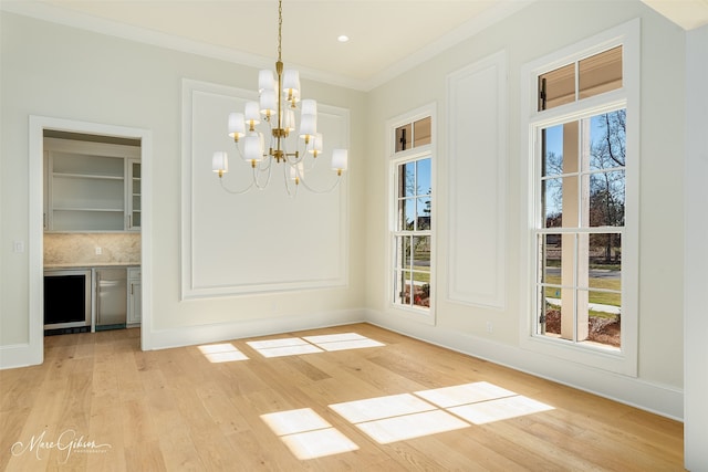 unfurnished dining area featuring crown molding, a chandelier, and light wood-type flooring