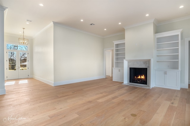 unfurnished living room featuring crown molding, a fireplace, light hardwood / wood-style floors, and a chandelier