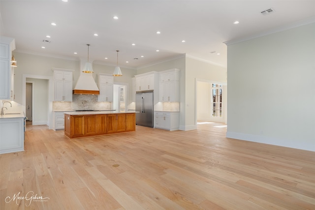 kitchen with sink, light hardwood / wood-style flooring, pendant lighting, a large island, and white cabinets