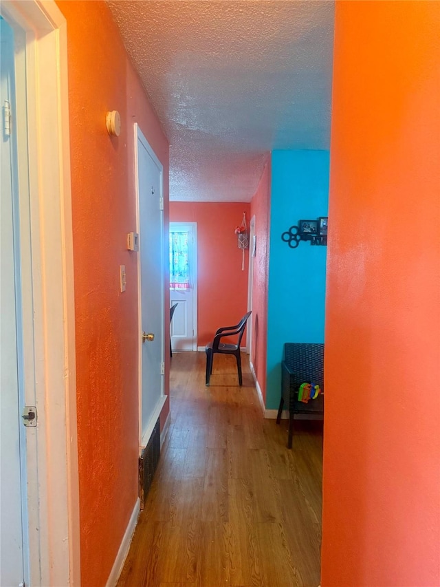 corridor featuring hardwood / wood-style flooring and a textured ceiling