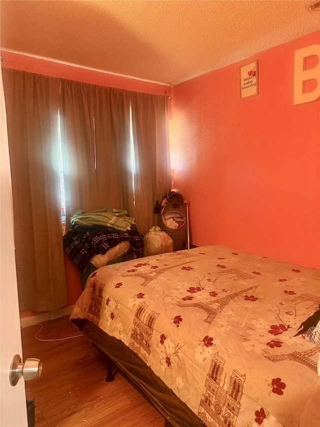 bedroom with a textured ceiling and hardwood / wood-style floors