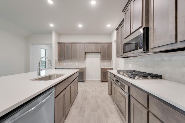 kitchen featuring decorative backsplash, stainless steel appliances, light countertops, a sink, and recessed lighting