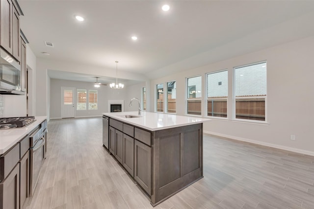 kitchen with appliances with stainless steel finishes, open floor plan, light countertops, and a sink