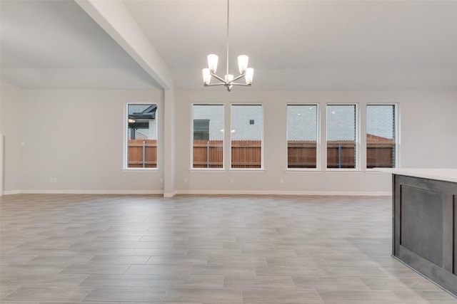 interior space featuring light wood-style floors, vaulted ceiling, a notable chandelier, and baseboards