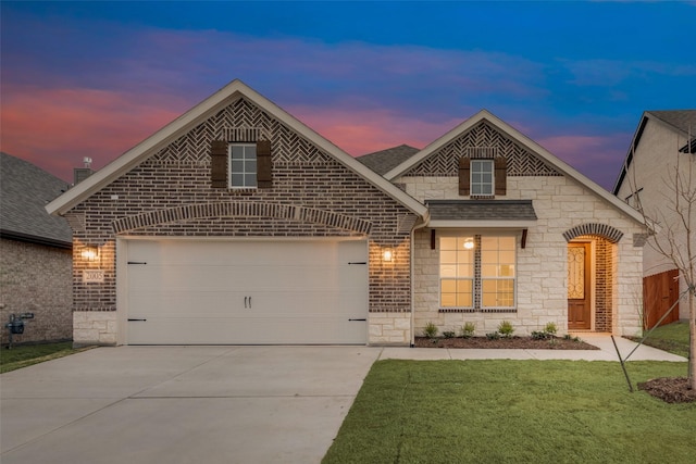 french country style house featuring concrete driveway, stone siding, roof with shingles, an attached garage, and a yard