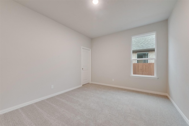 unfurnished room featuring baseboards and light colored carpet