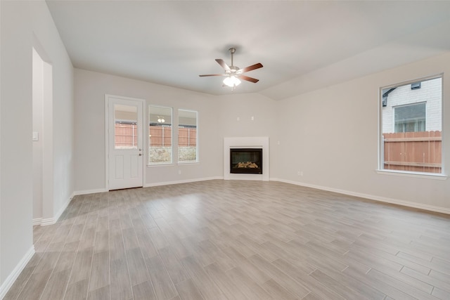 unfurnished living room featuring light wood-style flooring, baseboards, a ceiling fan, and a glass covered fireplace