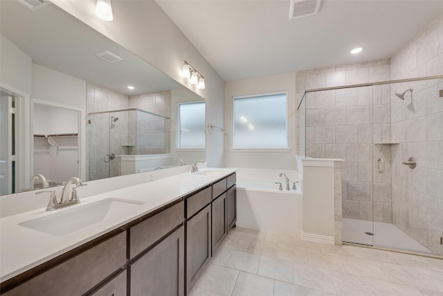 bathroom with visible vents, a sink, a shower stall, and a garden tub