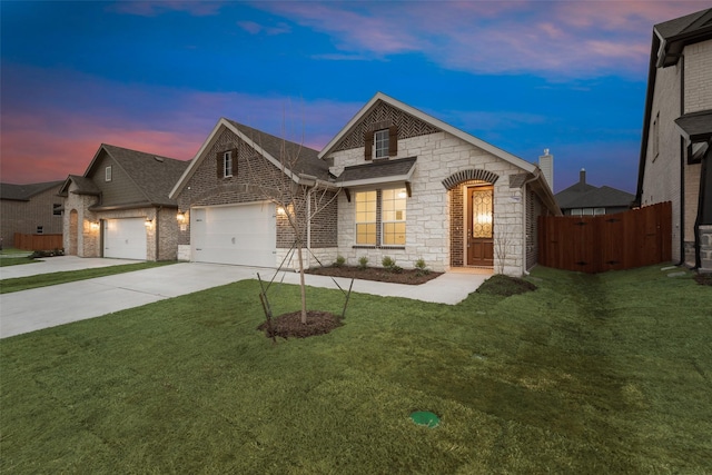 french country home with brick siding, concrete driveway, an attached garage, fence, and a front lawn