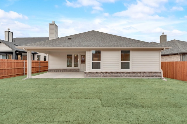 rear view of property with a patio, a fenced backyard, brick siding, roof with shingles, and a chimney