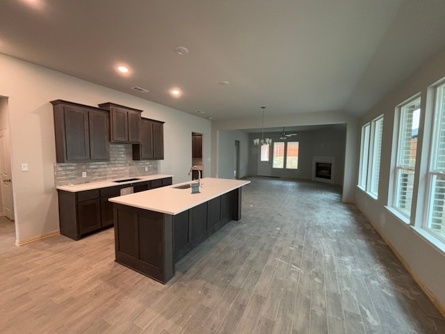 kitchen with dark brown cabinetry, sink, decorative backsplash, and light wood-type flooring