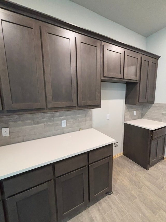 kitchen with backsplash, dark brown cabinetry, and light hardwood / wood-style floors