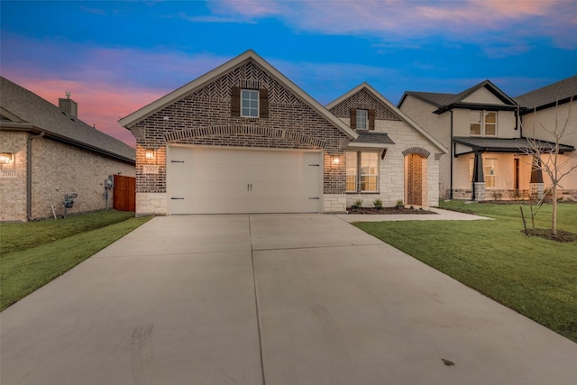 view of front facade with driveway, stone siding, an attached garage, a front lawn, and brick siding