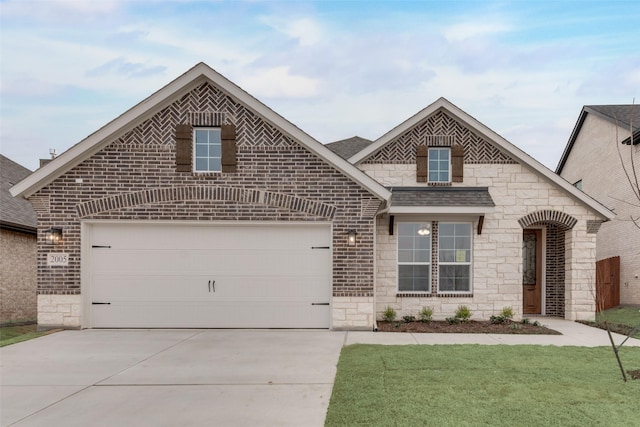 french country inspired facade featuring a garage, driveway, a shingled roof, and brick siding