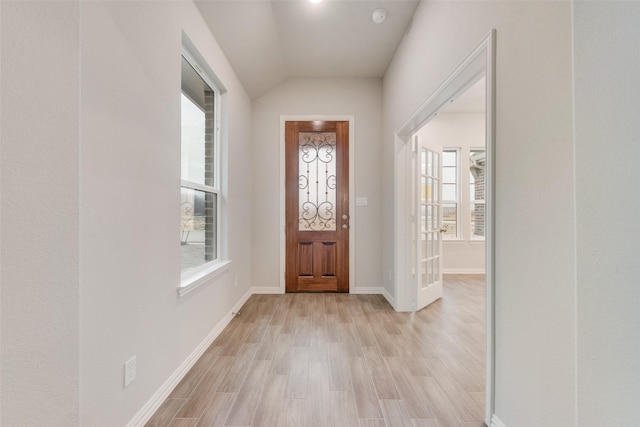 foyer with lofted ceiling, plenty of natural light, light wood-style flooring, and baseboards