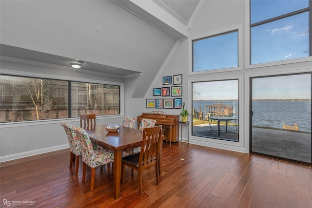 dining area with hardwood / wood-style flooring, a water view, crown molding, and vaulted ceiling