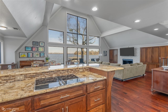 kitchen featuring dark wood-type flooring, black gas cooktop, light stone counters, high vaulted ceiling, and a fireplace