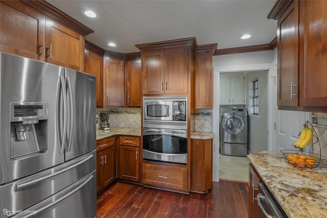 kitchen with stainless steel appliances, light stone counters, dark hardwood / wood-style floors, backsplash, and washer / dryer