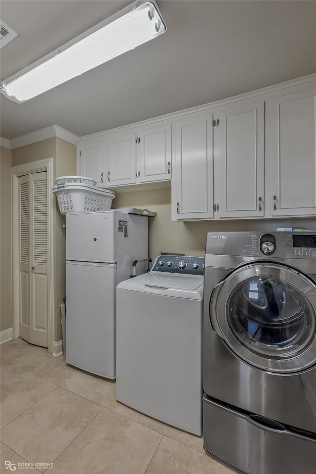 laundry room with washing machine and clothes dryer, crown molding, light tile patterned floors, and cabinets