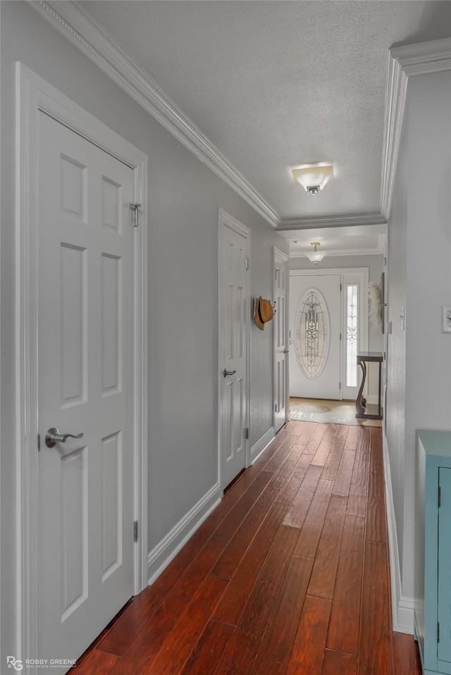 entryway featuring a textured ceiling, ornamental molding, and dark wood-type flooring