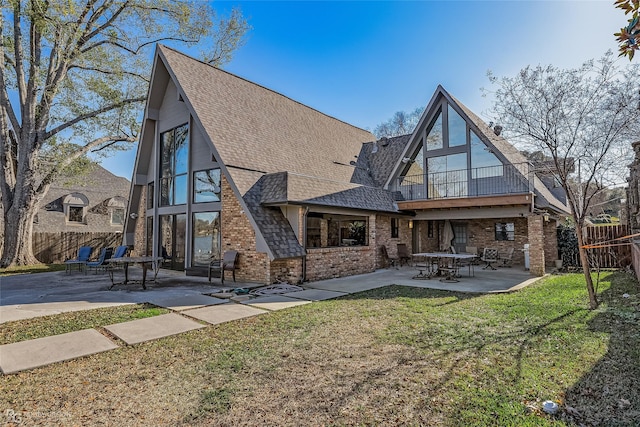 back of property with a lawn, a patio area, and a balcony