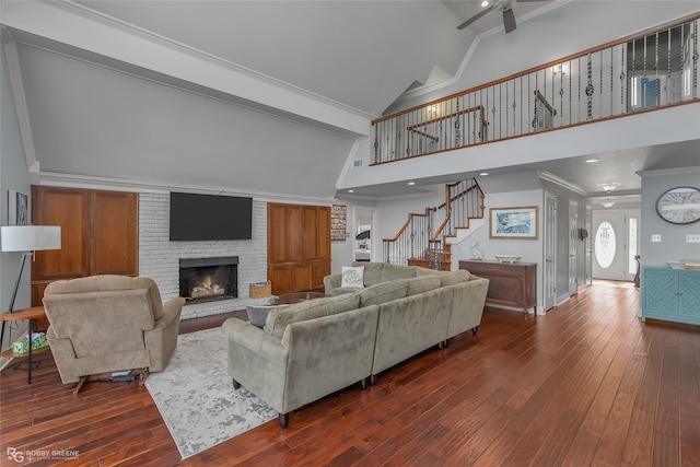 living room with ceiling fan, dark hardwood / wood-style flooring, high vaulted ceiling, a fireplace, and ornamental molding