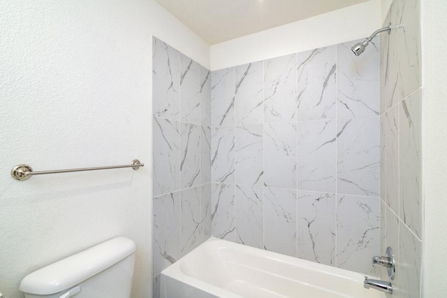 bathroom with tiled shower / bath combo and toilet