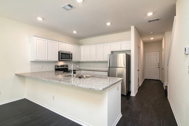 kitchen with white cabinets, appliances with stainless steel finishes, kitchen peninsula, and sink