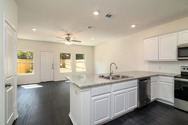 kitchen with stainless steel appliances, kitchen peninsula, sink, and white cabinets