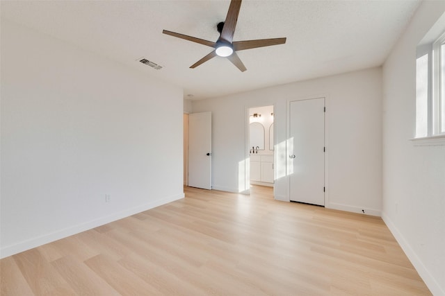 unfurnished bedroom featuring a textured ceiling, ceiling fan, light hardwood / wood-style floors, and ensuite bathroom