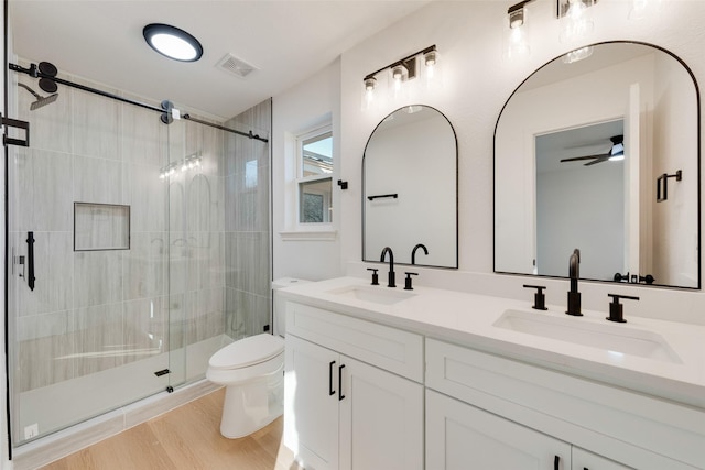 bathroom featuring vanity, hardwood / wood-style flooring, ceiling fan, toilet, and walk in shower