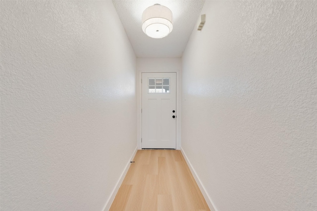 doorway with light wood-type flooring and a textured ceiling