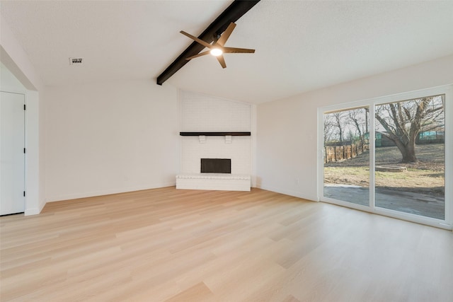 unfurnished living room featuring lofted ceiling with beams, light hardwood / wood-style floors, a fireplace, and ceiling fan