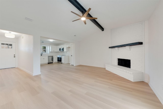 unfurnished living room featuring lofted ceiling with beams, light hardwood / wood-style floors, a brick fireplace, and ceiling fan