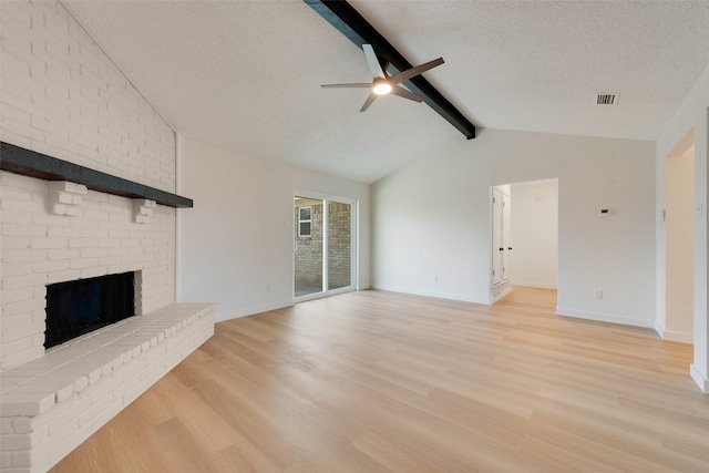 unfurnished living room with a textured ceiling, ceiling fan, a fireplace, vaulted ceiling with beams, and light hardwood / wood-style floors