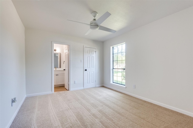 unfurnished bedroom with ensuite bath, ceiling fan, a closet, and light carpet