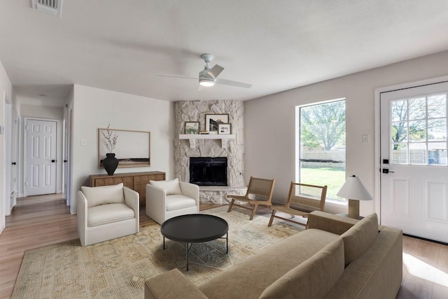 living room featuring a fireplace, wood-type flooring, and ceiling fan